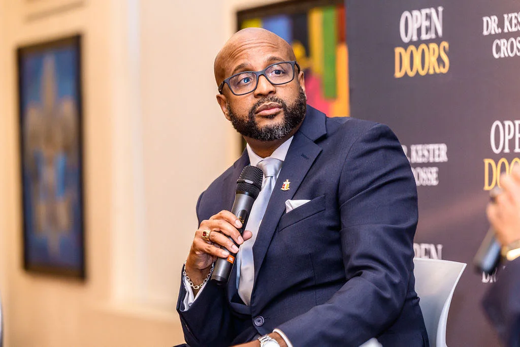 Dr. Kester Crosse speaking with a microphone in front of an Open Doors backdrop